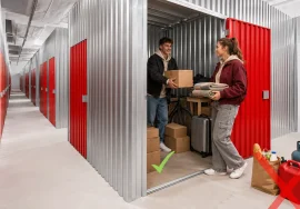 Fiatal pár dobozokat, bőröndöt és kerékpárt helyez el egy City Storage tárolóban, mellettük a tiltott tárgyak példái.