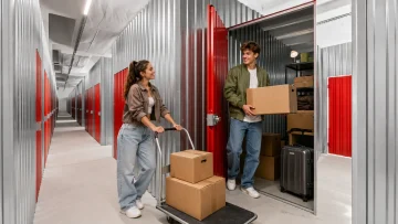 Young adults placing moving boxes in a self-storage unit in Budapest between rental apartments.